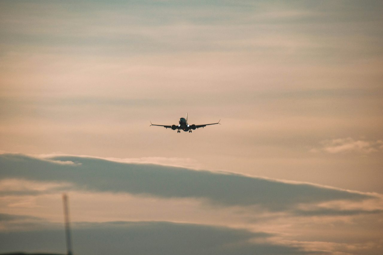 A commercial airliner in flight, silhouetted against a sunset sky