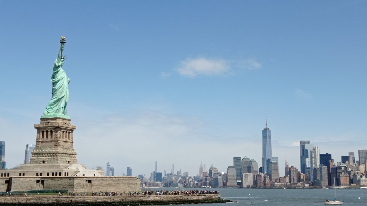 The Statue of Liberty with the New York City skyline behind it, under a clear sky