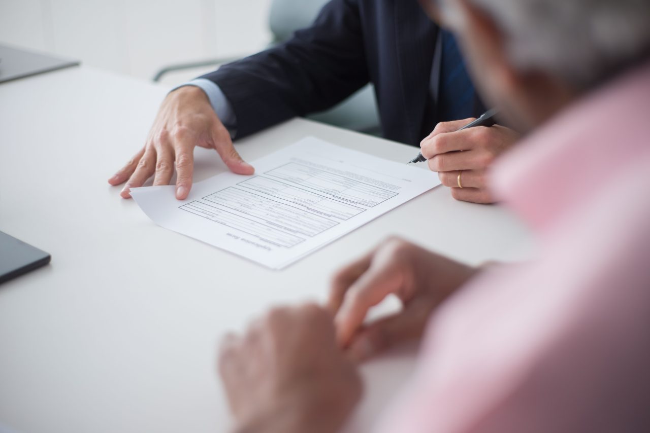Two people reviewing and signing paperwork at an office desk