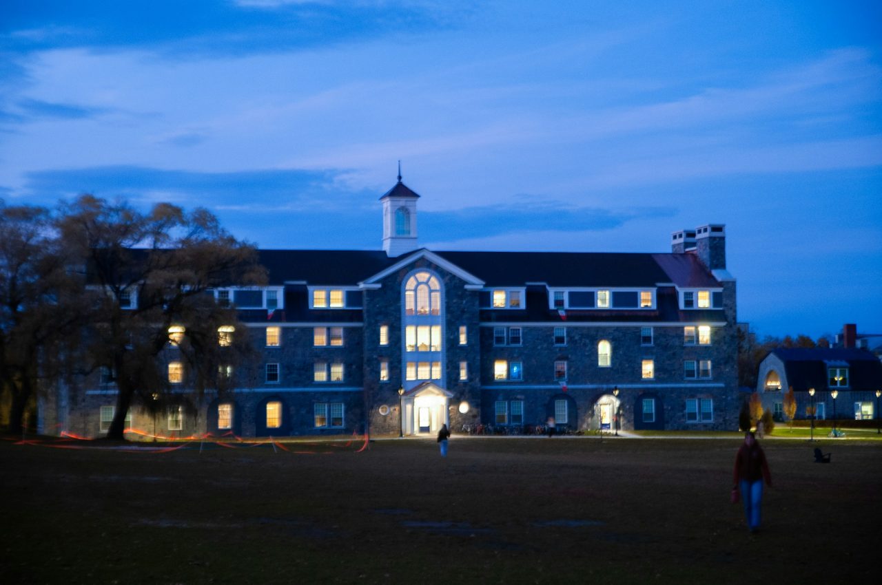A university building glowing warmly against a dusk sky.