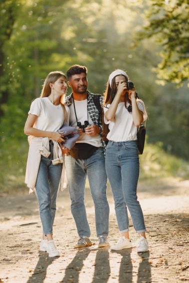 Adventure, travel, tourism, hike and people concept. Group of smiling friends in a forest.